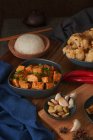 Mala Tofu, chinesisches veganes Gericht, begleitet von einer Schüssel Reis, Blumenkohl, Sojasauce und einer japanischen Teekanne auf einem mit Stoffen dekorierten Holztisch — Stockfoto