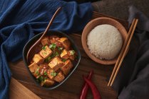 Close up mala tofu, prato vegan chinês, acompanhado por uma tigela de arroz em cima de uma mesa de madeira decorada com tecidos — Fotografia de Stock
