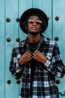 African American male in trendy outfit and sunglasses standing and looking at camera near doorway — Foto stock