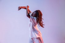 Full body of concentrated African American teen dancing in studio with bright neon light — Stock Photo