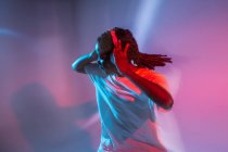Grave menina adolescente afro-americana em fones de ouvido dançando em estúdio com luzes brilhantes de néon — Fotografia de Stock