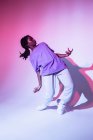 Повний гурт афроамериканської дівчини-підлітка, що виконує міський танцювальний рух у яскравій студії. — стокове фото