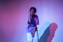 African American teenage girl enjoying music in headphones in neon studio — Stock Photo