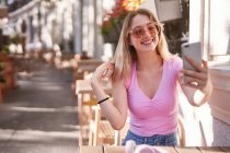 Cheerful woman taking selfie while sitting at table in street cafe in Madrid — Foto stock