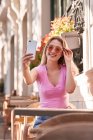 Cheerful woman taking selfie while sitting at table in street cafe in Madrid — Fotografia de Stock