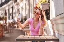 Fröhliche Frau macht Selfie, während sie am Tisch im Straßencafé in Madrid sitzt — Stockfoto