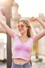 Happy female with hands raised standing in sunshine during trip in Madrid — Foto stock