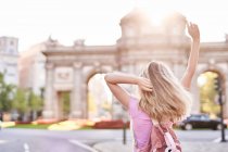 Rückseite weiblich mit erhobenen Händen in der Sonne stehend während der Fahrt in Madrid — Stockfoto