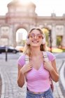 Glückliche Frau steht während einer Reise in Madrid in der Sonne und blickt in die Kamera — Stockfoto