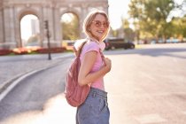 Happy female standing in sunshine during trip in Madrid and looking at camera — Stock Photo
