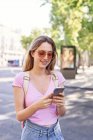 Молода жінка йде по пішохідній переправі й перевіряє маршрут по мобільному телефону в Мадриді. — стокове фото