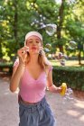 Insouciante femme soufflant des bulles tout en passant une journée ensoleillée dans le parc vert de Madrid — Photo de stock