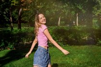 Allegro femmina in piedi in spruzzi nel parco soleggiato — Foto stock