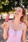 Fröhliche Frau im Sommerkleid steht mit Eis am Stiel und genießt den sonnigen Tag in Madrid — Stockfoto
