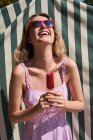 Fröhliche Frau im Sommerkleid steht mit Eis am Stiel und genießt den sonnigen Tag in Madrid — Stockfoto