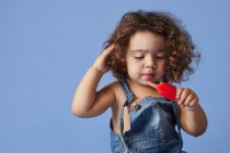 Sconvolto bambina in piedi con gelato contro studio sfondo blu — Foto stock