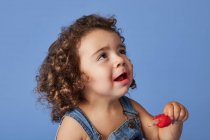 Sconvolto bambina guardando in piedi con il gelato contro lo studio sfondo blu — Foto stock