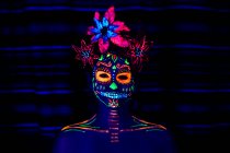 Anonymes Weibchen in bunter Maskerade mit Blumen auf dem Kopf blickt in der Halloween-Nacht in die Kamera — Stockfoto