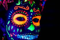 Анонімна жінка в різнокольоровій маскарадній масці з квітами на голові дивиться на камеру в ніч на Хеллоуїн — стокове фото
