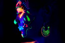 Mulher anônima em máscara de máscaras multicoloridas com flores na cabeça olhando para longe na noite de Halloween — Fotografia de Stock