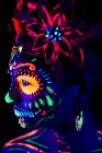 Anonymous female in multicolored masquerade mask with flowers on head looking away on Halloween night — Stock Photo