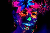 Anonymous female in multicolored masquerade mask with flowers on head looking at camera on Halloween night — Stock Photo