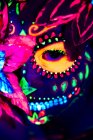 Анонимная женщина в разноцветной маскарадной маске с цветами на голове, смотрящая в камеру в ночь Хэллоуина — стоковое фото