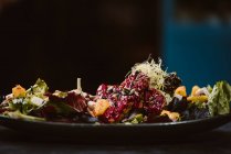 Низкий угол обзора тарелки с вкусным вегетарианским индонезийским салатом со свежими ломтиками манго и кешью рядом с соевыми бобами и приправами, покрытыми базиликовым винегретом — стоковое фото