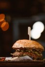 Baixo ângulo de hambúrguer gostoso com patty vegetariano e shiitakes grelhados entre pães perto de batata-doce e fatias de cenoura com molho de álioli no fundo escuro — Fotografia de Stock