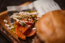 Nahaufnahme von leckeren Burgern mit vegetarischem Patty und gegrillten Shiitakes zwischen Brötchen in der Nähe von Süßkartoffel- und Karottenscheiben mit Alioli-Sauce auf dunklem Hintergrund — Stockfoto