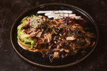 De cima do prato vegan gostoso com espaguete de abobrinha e fatias de cogumelos refogados cobertas com bagas vermelhas e brotos de alfafa no fundo escuro — Fotografia de Stock