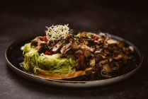 Leckeres veganes Gericht mit Zucchini-Spaghetti und sautierten Pilzscheiben mit roten Beeren und Luzernesprossen auf dunklem Hintergrund — Stockfoto