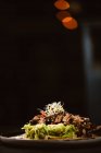 Basso angolo di gustoso piatto vegano con spaghetti di zucchine e fette di funghi saltati ricoperte di bacche rosse e germogli di erba medica su sfondo scuro — Foto stock