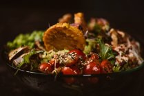 Ciotola di gustose fette di patate dolci con pomodorini vicino a piselli verdi e semi di sesamo su sfondo scuro — Foto stock