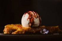 Niedrige Ansicht von leckeren French Toast mit Baiser-Milch-Eiskugel mit süßer Beerensauce auf Teller mit Gewürzen im Restaurant auf dunklem Hintergrund bedeckt — Stockfoto