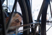 Mecânico masculino concentrado com barba em luvas reparando bicicleta na oficina moderna — Fotografia de Stock