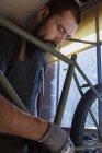 Colheita mecânico masculino em luvas de reparação de bicicleta na oficina moderna — Fotografia de Stock