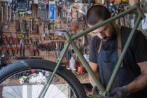 Mecânico masculino em luvas de reparação de bicicleta na oficina moderna — Fotografia de Stock