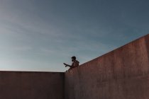 From below of young bearded male skater standing on high concrete ramp in skatepark with skateboard looking away — Fotografia de Stock