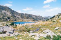 Magnífico paisaje de áspera cordillera rocosa que rodea el tranquilo lago azul bajo el cielo azul claro en el soleado día de verano en los Pirineos Catalanes - foto de stock