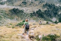 Back view of anonymous backpackers walking on mountain during summer trip — Foto stock