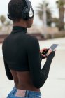 Назад перегляд етнічних повідомлень жіночого тексту на мобільному телефоні з чорним екраном у місті — стокове фото