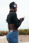 Indietro visualizza messaggi di testo etnici femminili sul telefono cellulare con schermo nero in città — Foto stock