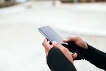 Обрізати анонімні етнічні текстові повідомлення жінок на мобільний телефон з чорним екраном у місті — стокове фото