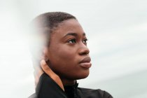 Junge kontemplative ethnische Frau mit kurzen Haaren berührt Gesicht bei Tageslicht — Stockfoto