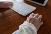 Анонимный урожай пациента с клавиатурой против планшета с врачом на экране во время видеозвонка в доме — стоковое фото
