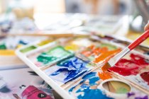 Schnitte anonymer Maler Mischen von Farben mit Pinsel mit Aquarellpalette während der Arbeit im Kunstatelier — Stockfoto