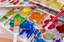 Crop anonymous painter mixing paints with brush using watercolor palette while working in art studio — Foto stock