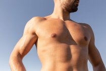 Atleta maschio determinato con forte busto nudo in piedi sulla collina erbosa nella giornata di sole in estate e guardando lontano — Foto stock