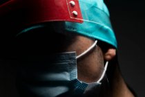 Closeup de cirurgião masculino em máscara médica olhando para longe no quarto escuro — Fotografia de Stock